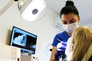 zubarka popravlja zube pacijentu sa upaljenim svetlom